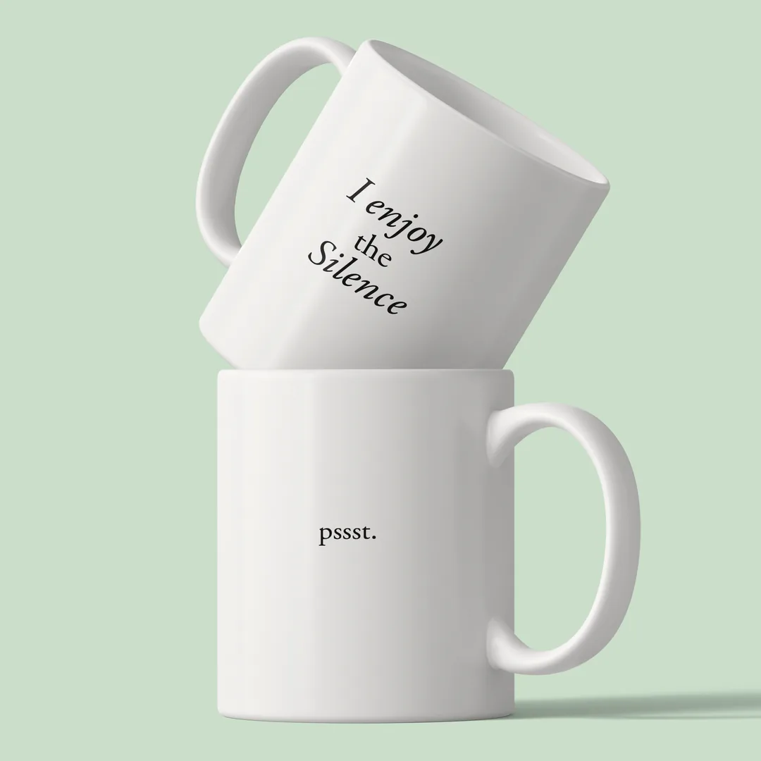 Two stacked I Enjoy The Silence mugs on a mint green background, the slogan on top, pssst. below