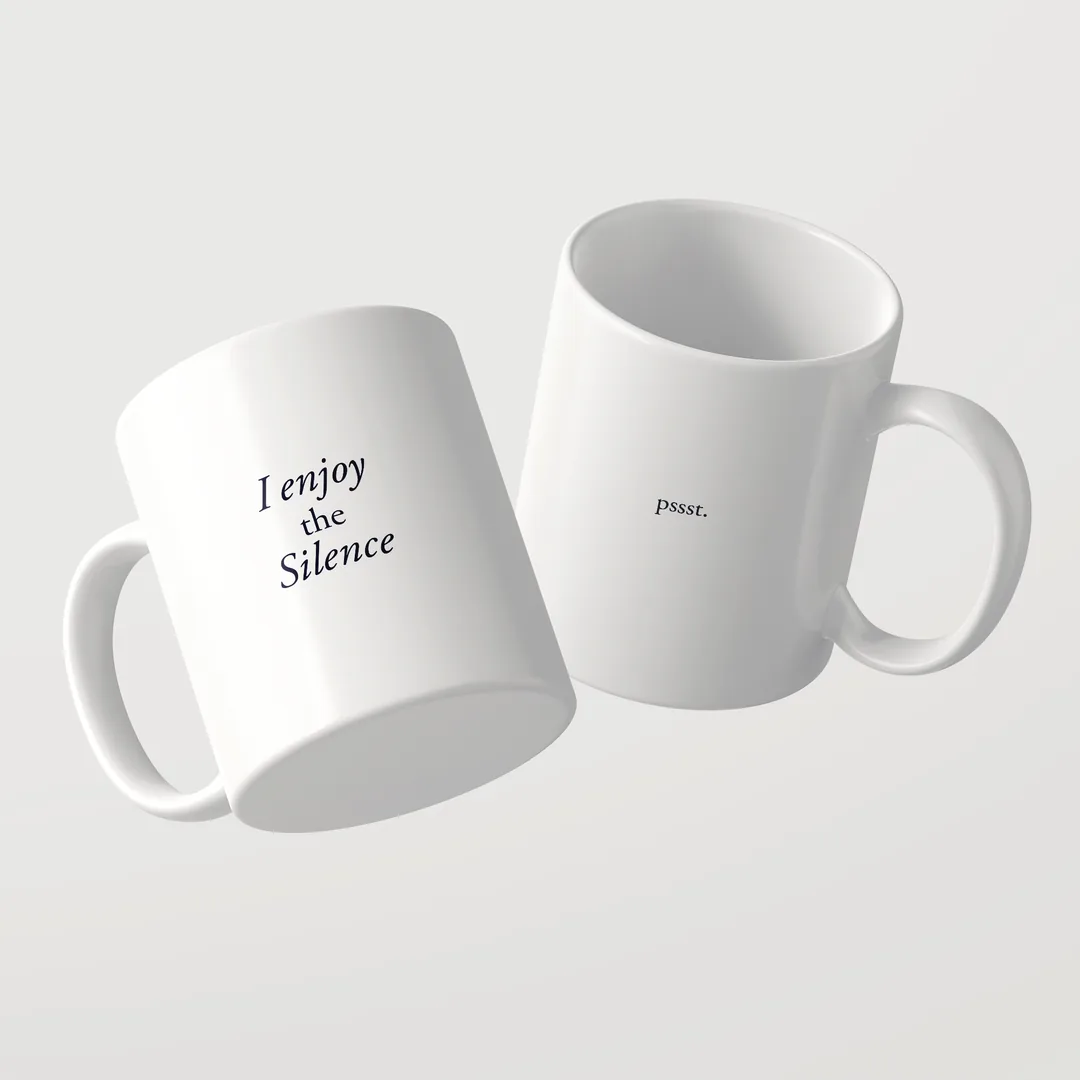 Two white I Enjoy The Silence mugs by Studio SaySay, one reading I enjoy the Silence, the other pssst.