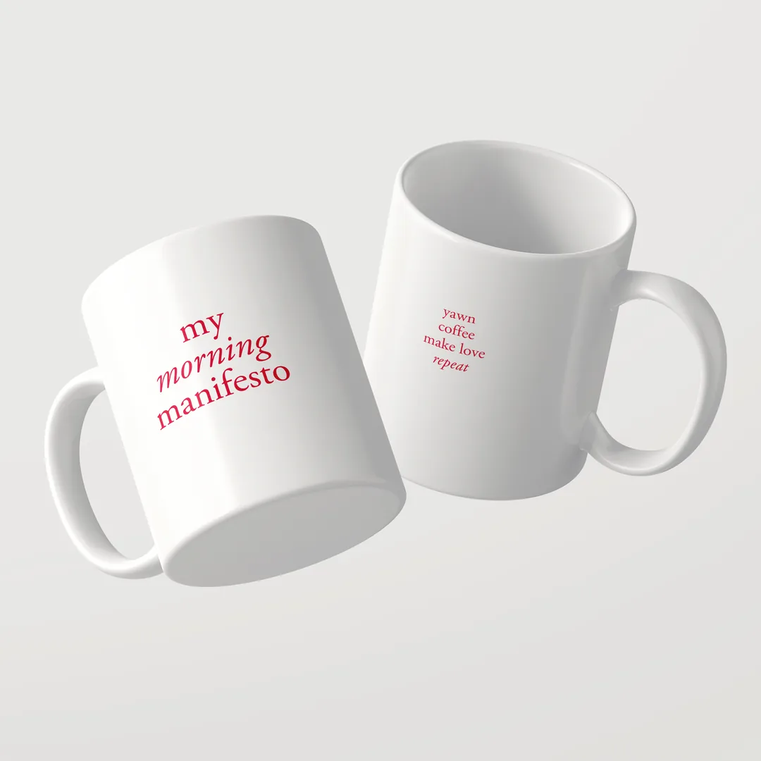 Zwei weiße My Morning Manifesto Tassen mit roter Schrift: eine zeigt den Titel, die andere yawn, coffee, make love, repeat