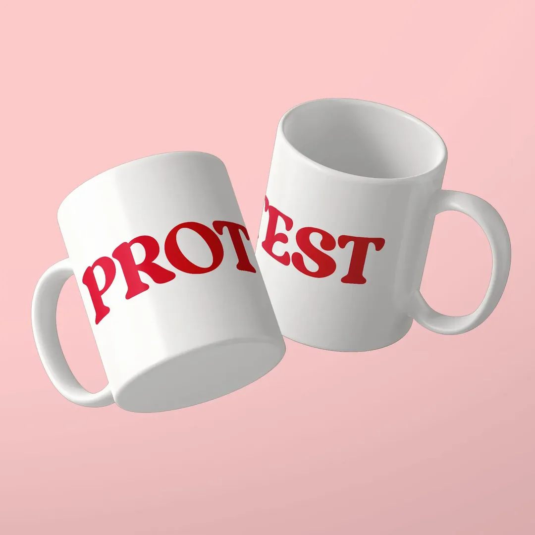 Two white mugs with the red lettering PROTEST