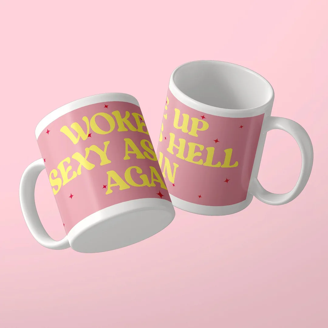 Zwei rosa Woke Up Sexy As Hell Again Tassen von Studio SaySay mit gelbem Spruch und roten Sternchen